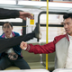 Simu Liu's Shang-Chi punches a goon on a city bus while Awkwafina's Katy gasps in shock.